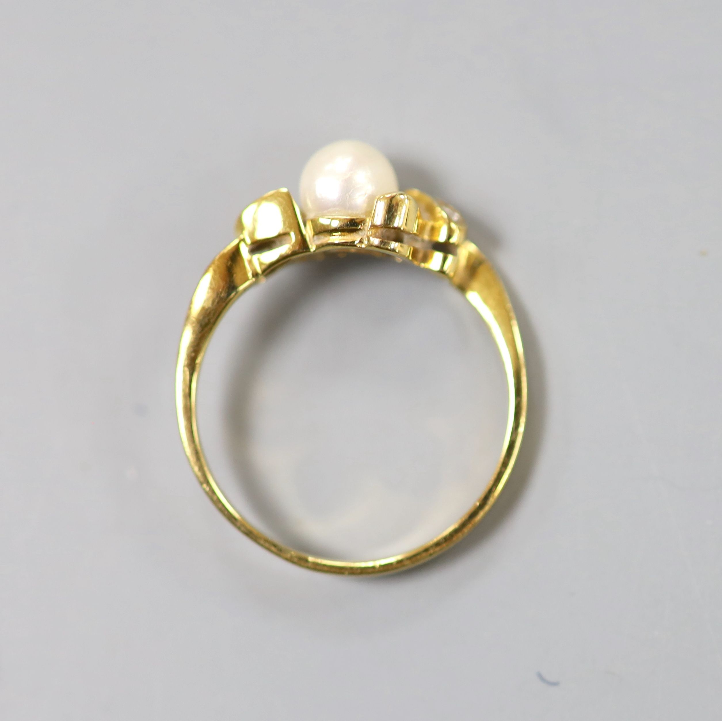 An 18k, single stone cultured pearl and two stone diamond chip set ring, size J, gross 1.9 grams.